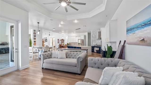 living room featuring a ceiling fan, light wood-style flooring, recessed lighting, crown molding, and a raised ceiling