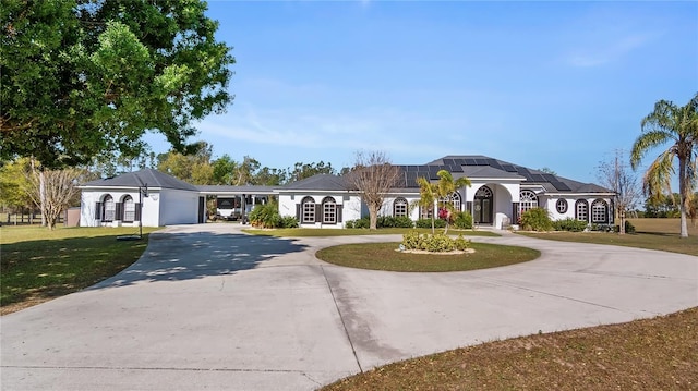 view of front of house featuring solar panels, a front lawn, stucco siding, and curved driveway