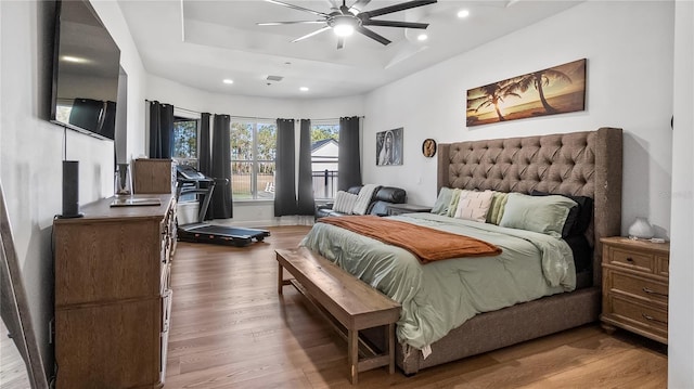 bedroom with recessed lighting, baseboards, a tray ceiling, and wood finished floors