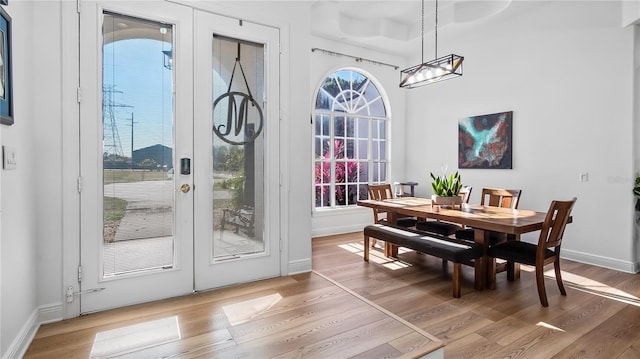 dining area with a chandelier, baseboards, french doors, and light wood-type flooring