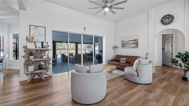 living room with wood finished floors, ceiling fan, a healthy amount of sunlight, and crown molding