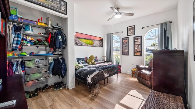bedroom with wood finished floors, ceiling fan, baseboards, and a closet