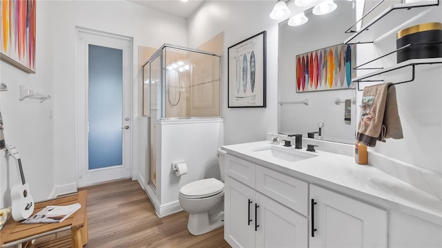 full bathroom featuring a shower stall, vanity, toilet, baseboards, and wood finished floors