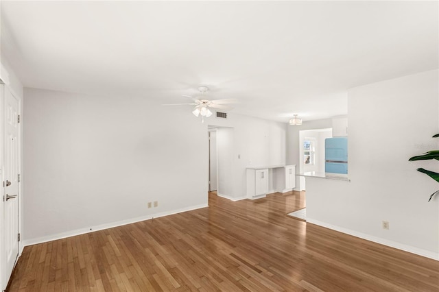 unfurnished living room with ceiling fan, wood finished floors, visible vents, and baseboards