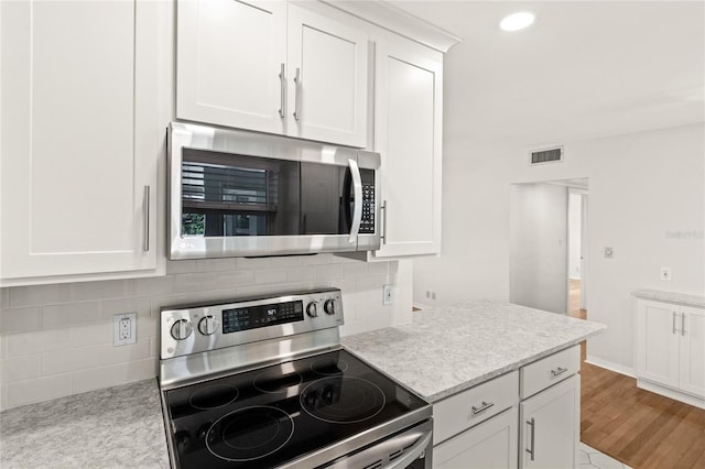 kitchen featuring white cabinets, visible vents, stainless steel appliances, and decorative backsplash