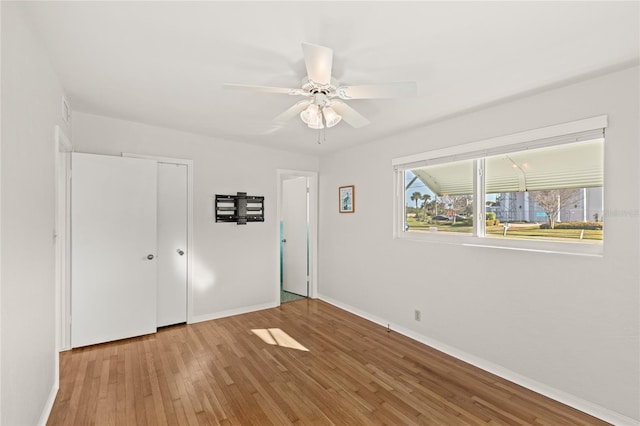 unfurnished bedroom with a closet, ceiling fan, baseboards, and wood finished floors