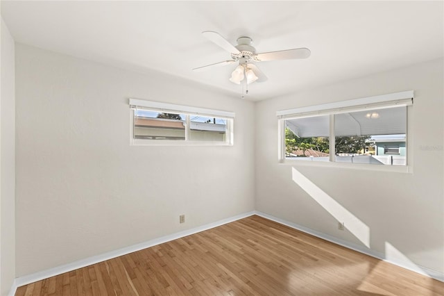 empty room with wood finished floors, a ceiling fan, and baseboards