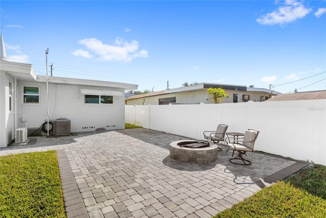 view of patio featuring cooling unit, a fenced backyard, and a fire pit