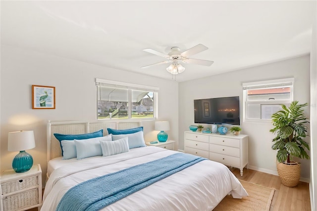 bedroom with ceiling fan, light wood-style flooring, and baseboards