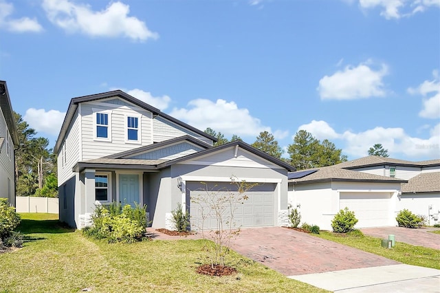 traditional-style home with decorative driveway, stucco siding, fence, a garage, and a front lawn