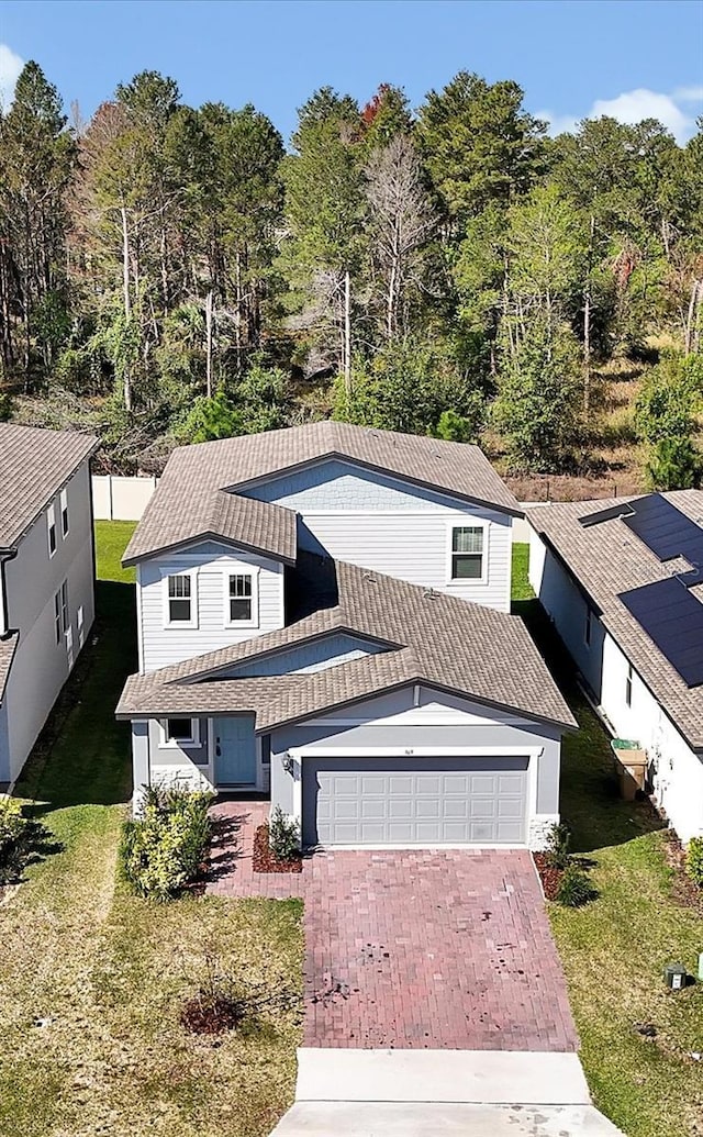 view of front of house with an attached garage, decorative driveway, a front yard, and a tile roof