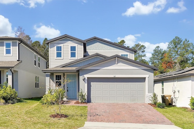 traditional-style house with decorative driveway, an attached garage, and a front lawn