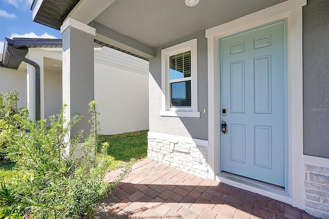 doorway to property featuring stone siding and stucco siding