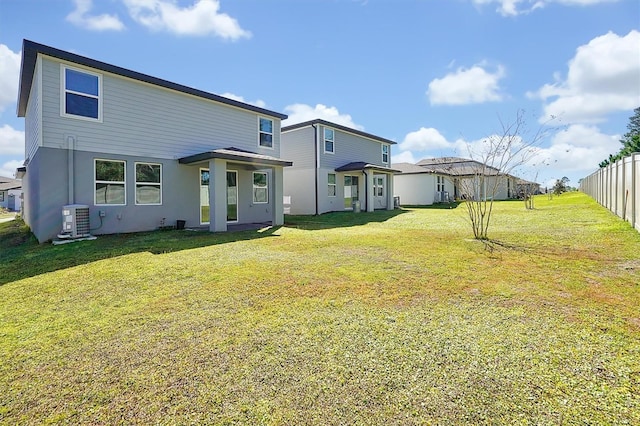 back of property with fence, central AC unit, and a lawn