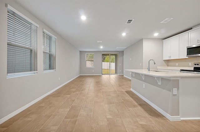 kitchen featuring visible vents, stainless steel microwave, light countertops, and a sink