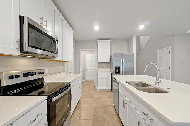 kitchen featuring a sink, white cabinets, light countertops, appliances with stainless steel finishes, and an island with sink