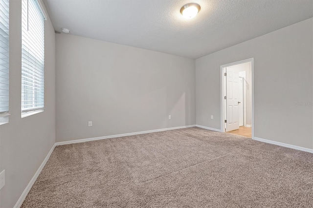 unfurnished room with baseboards, a textured ceiling, and light colored carpet