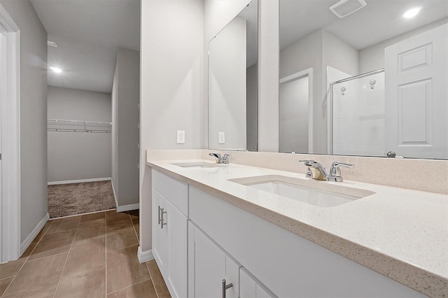 full bath featuring a stall shower, visible vents, a walk in closet, and a sink