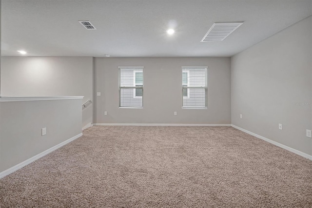 unfurnished room with carpet floors, visible vents, and baseboards