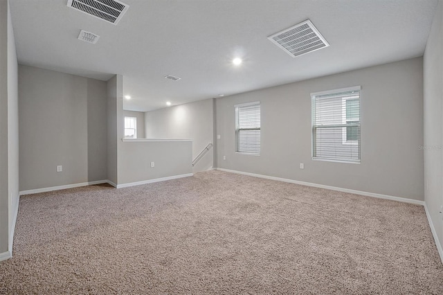 spare room featuring carpet floors, visible vents, and baseboards