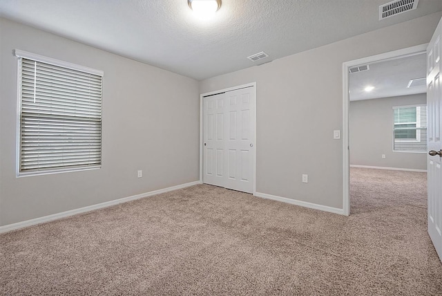 unfurnished bedroom featuring light colored carpet, a closet, visible vents, and baseboards