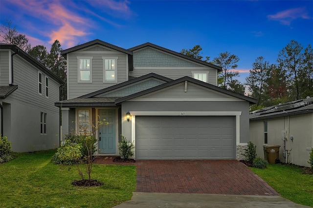 view of front of home with a garage, decorative driveway, and a yard