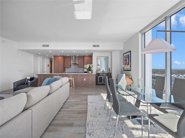 living area with visible vents, baseboards, light wood-style floors, and expansive windows