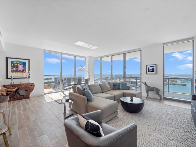 living area with expansive windows, a water view, and wood finished floors