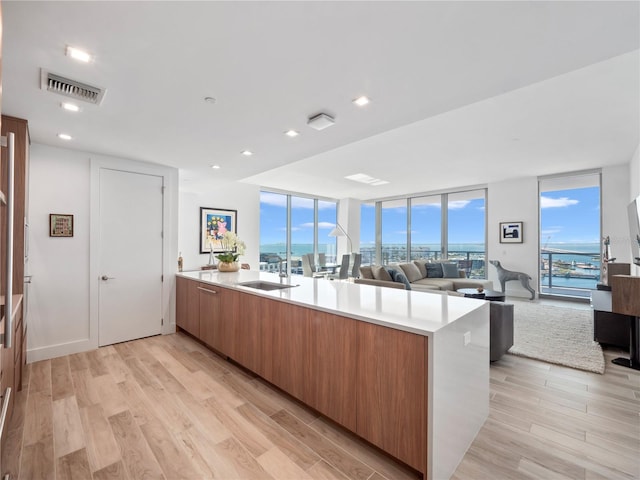 kitchen with brown cabinetry, visible vents, light wood-style flooring, and light countertops