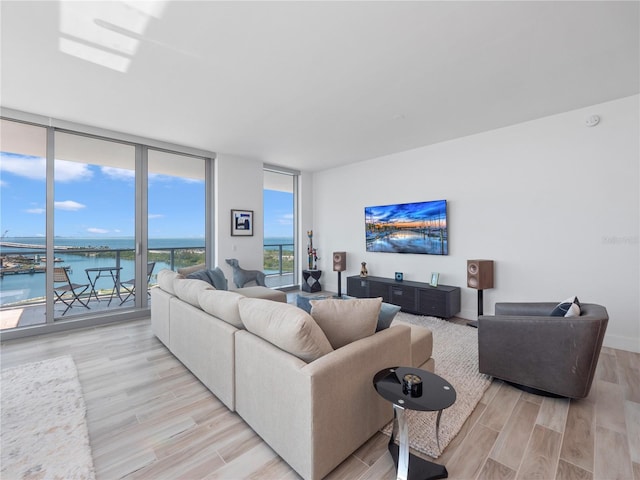 living room with light wood finished floors, floor to ceiling windows, and a water view