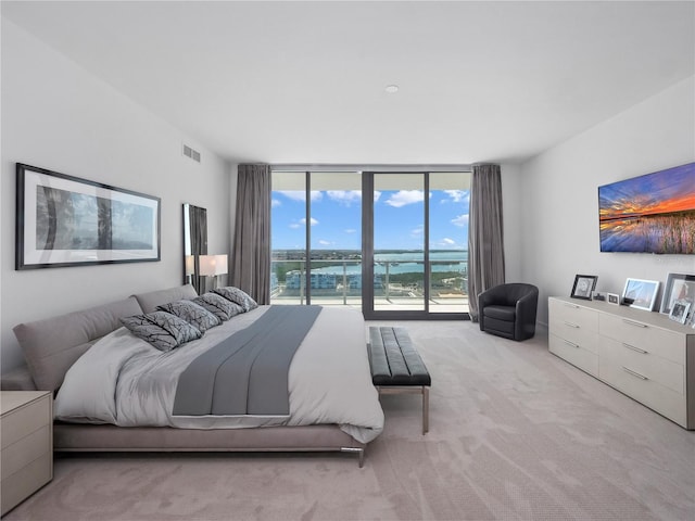 bedroom with access to exterior, visible vents, carpet, and expansive windows