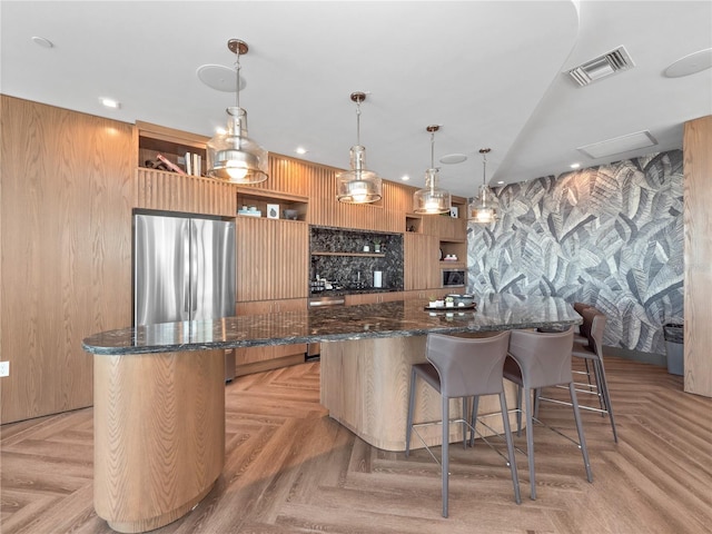 kitchen with visible vents, a breakfast bar, open shelves, a spacious island, and freestanding refrigerator