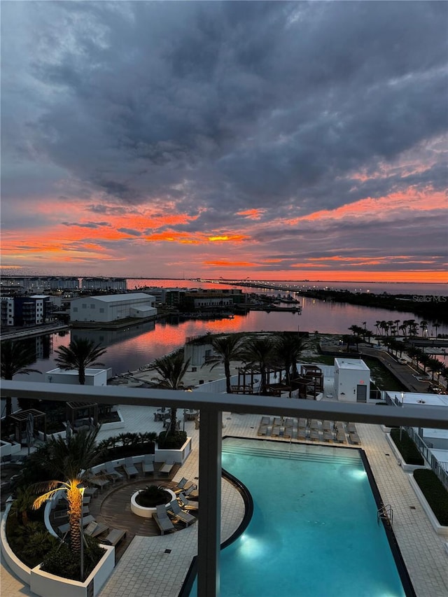 pool at dusk featuring a water view