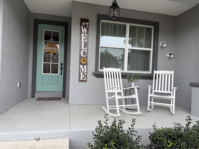 property entrance featuring a porch and stucco siding