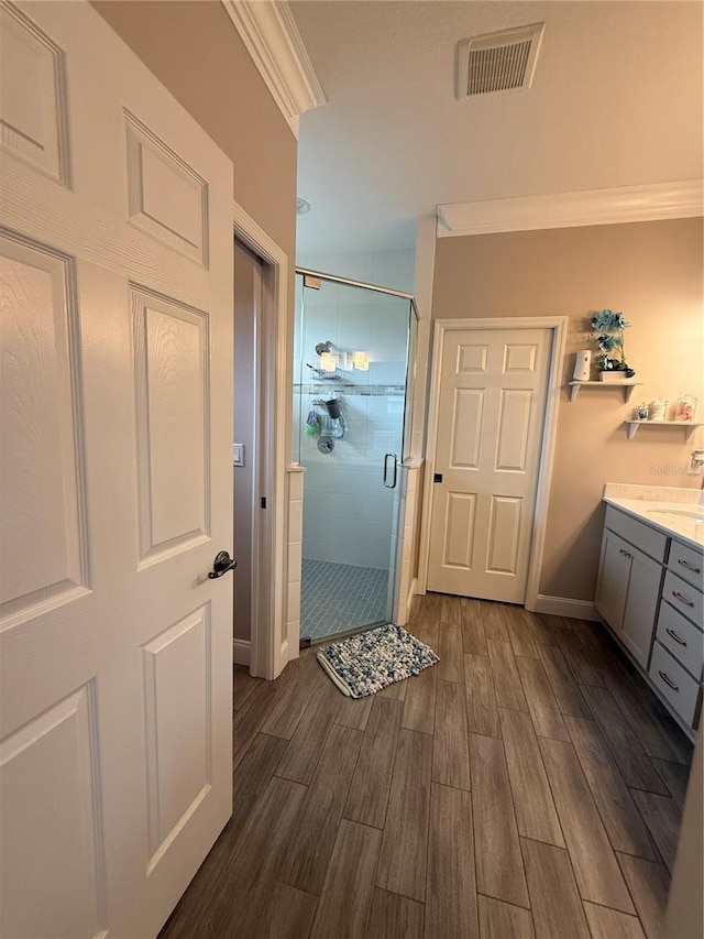 full bath with wood finish floors, crown molding, visible vents, a shower stall, and vanity