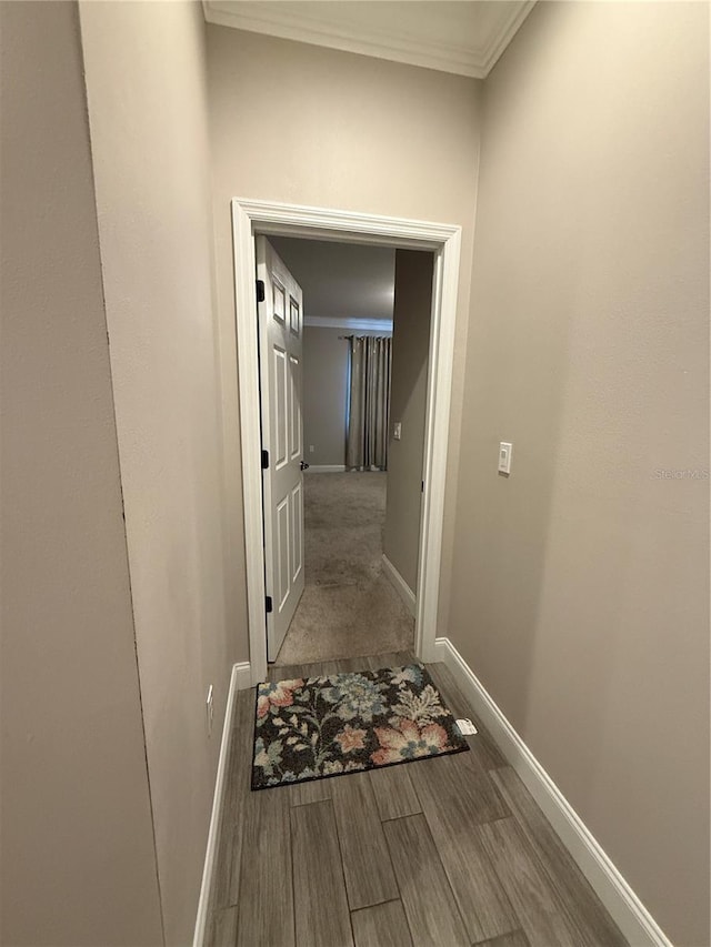 hallway with baseboards, wood finished floors, and ornamental molding