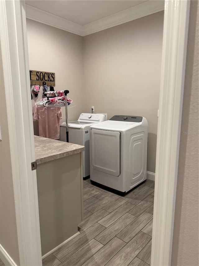 laundry area featuring crown molding, light wood finished floors, washing machine and dryer, laundry area, and baseboards