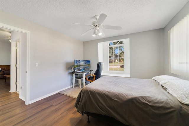 bedroom with a ceiling fan, dark wood-style flooring, a textured ceiling, and baseboards