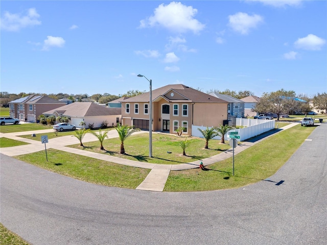 view of front of house with driveway, a residential view, fence, a front yard, and stucco siding