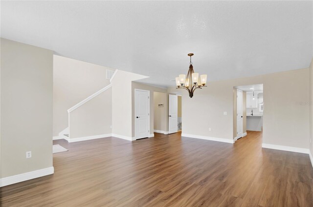 unfurnished living room featuring stairs, wood finished floors, and baseboards