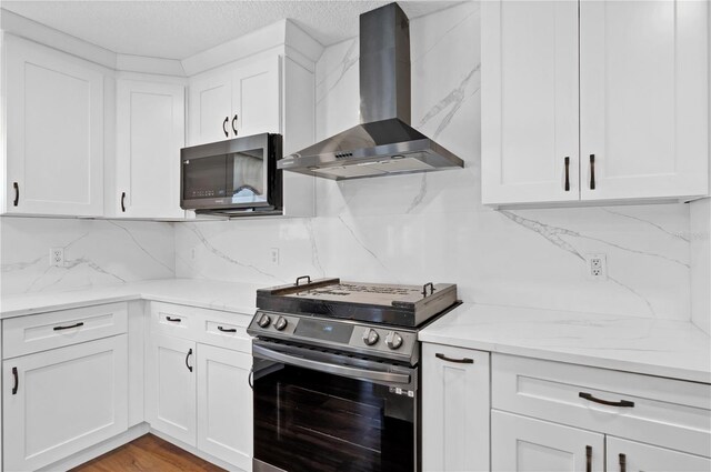 kitchen with white cabinets, wall chimney exhaust hood, light stone countertops, stainless steel appliances, and backsplash