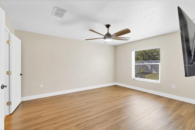 unfurnished room with light wood finished floors, visible vents, a ceiling fan, a textured ceiling, and baseboards