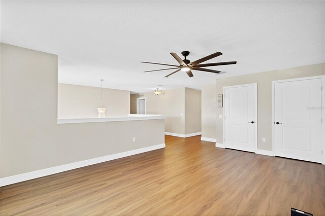 unfurnished room featuring ceiling fan, light wood-style flooring, and baseboards