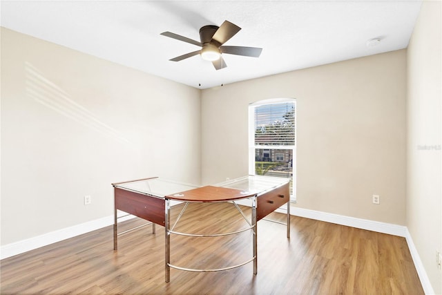 unfurnished office with a ceiling fan, baseboards, and wood finished floors