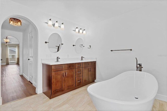 bathroom featuring double vanity, a freestanding tub, baseboards, and a sink