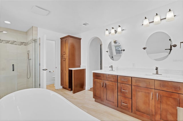 bathroom featuring double vanity, a sink, visible vents, and a shower stall