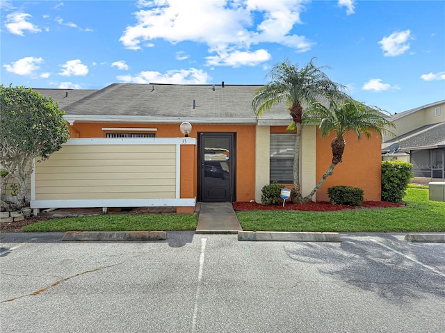 single story home with a shingled roof, uncovered parking, and stucco siding