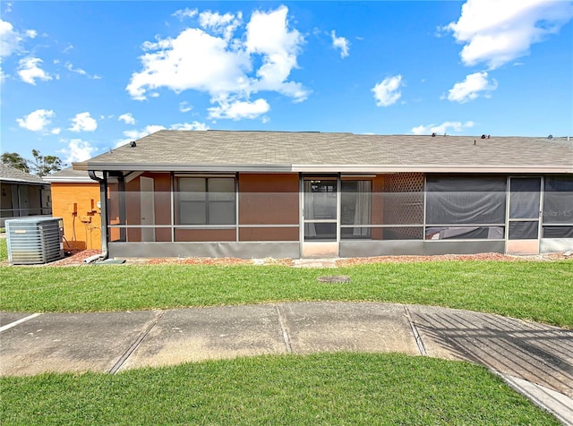 back of house featuring a shingled roof, a lawn, a sunroom, and central air condition unit