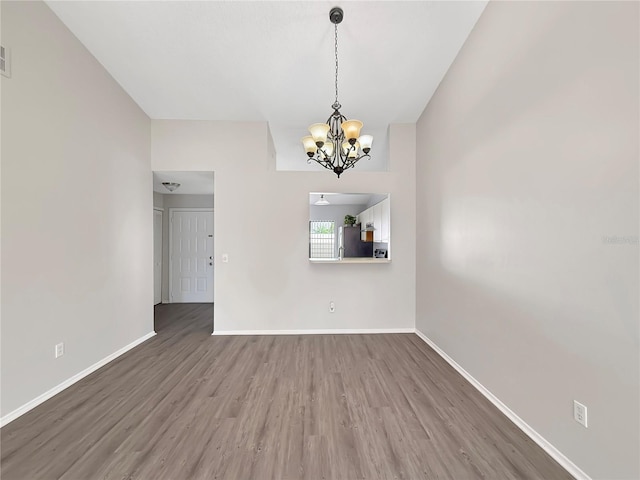 unfurnished room with a chandelier, visible vents, baseboards, and wood finished floors