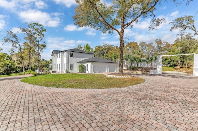 view of front of home with a front yard, decorative driveway, and an attached garage